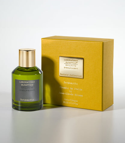 A green glass bottle of Bergamotto Eau de Parfum by Laboratorio Olfattivo stands next to a yellow box with a gold label, both displayed on a light surface, reflecting Italian fragrance artistry.