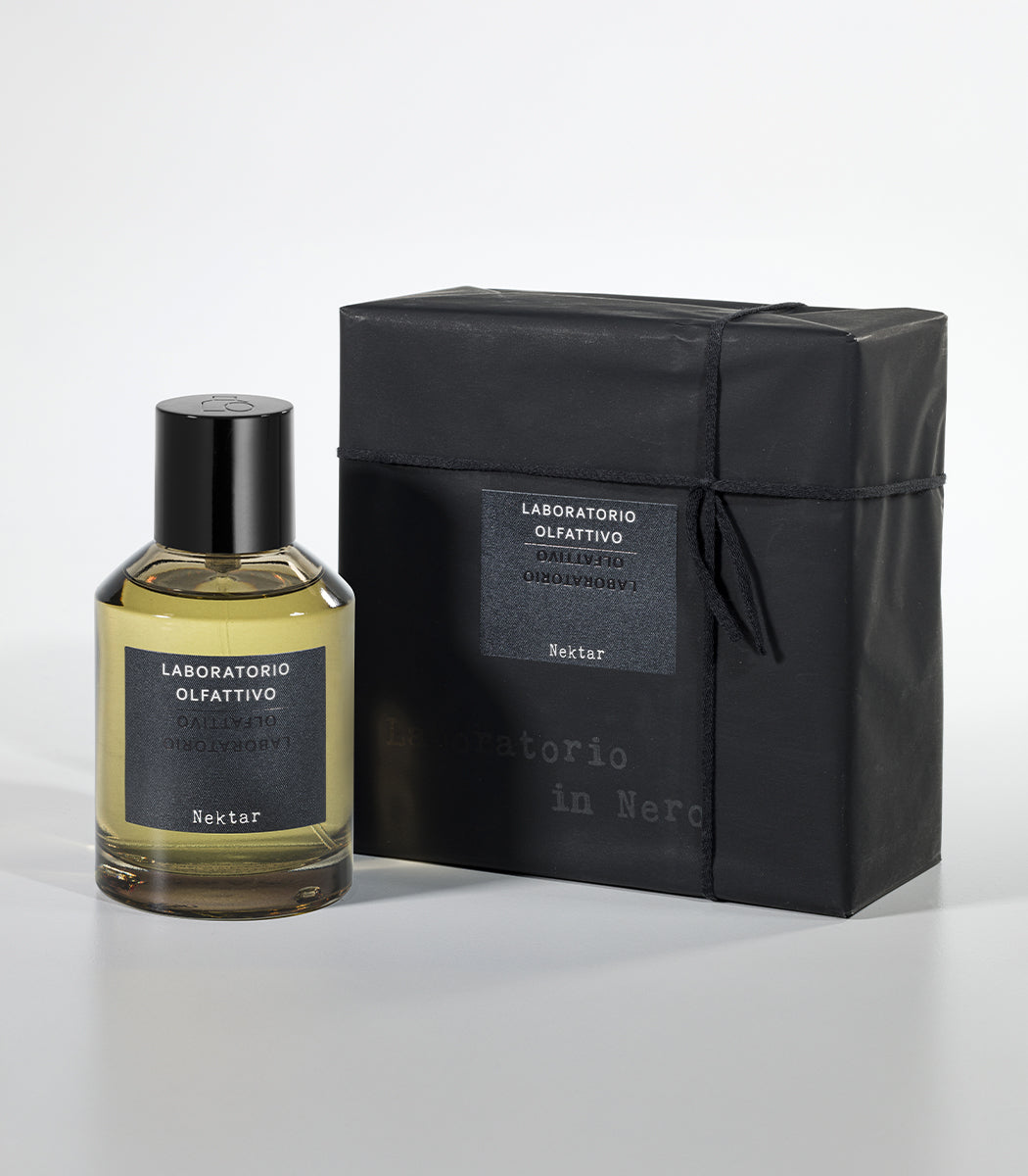 A bottle of Nektar Eau de Parfum by Laboratorio Olfattivo, inspired by Sidr Honey, sits beside its black minimalist box against a light gray background.