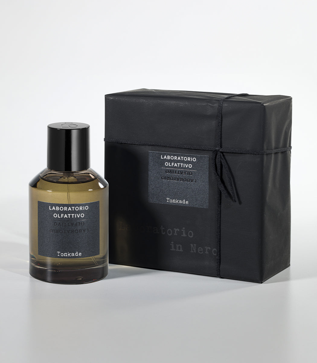 A bottle of Tonkade Eau de Parfum by Laboratorio Olfattivo sits beside its sleek black box with a matching label, both displayed on a plain light gray background, evoking the inviting essence of Tonka Bean.