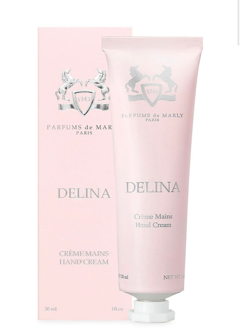 A pink tube of Parfums de Marly Delina Hand Cream stands before its matching box, both with silver accents and elegant branding—offering a touch of luxury.