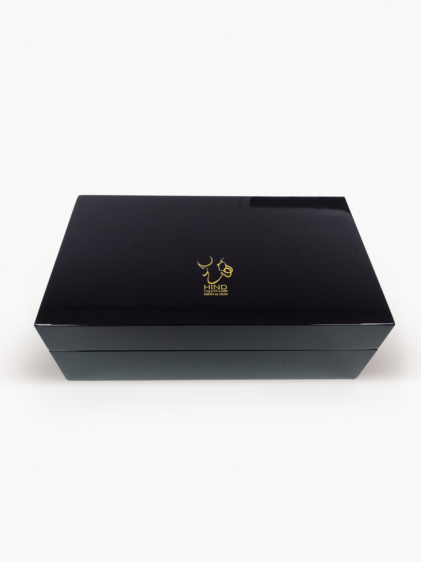 A sleek, rectangular black Emarati Musk Trio Shield Edition Gift Box by Hind Al Oud showcases a gold abstract logo on the lid, set against a white background—ideal for presenting your favorite fragrances.