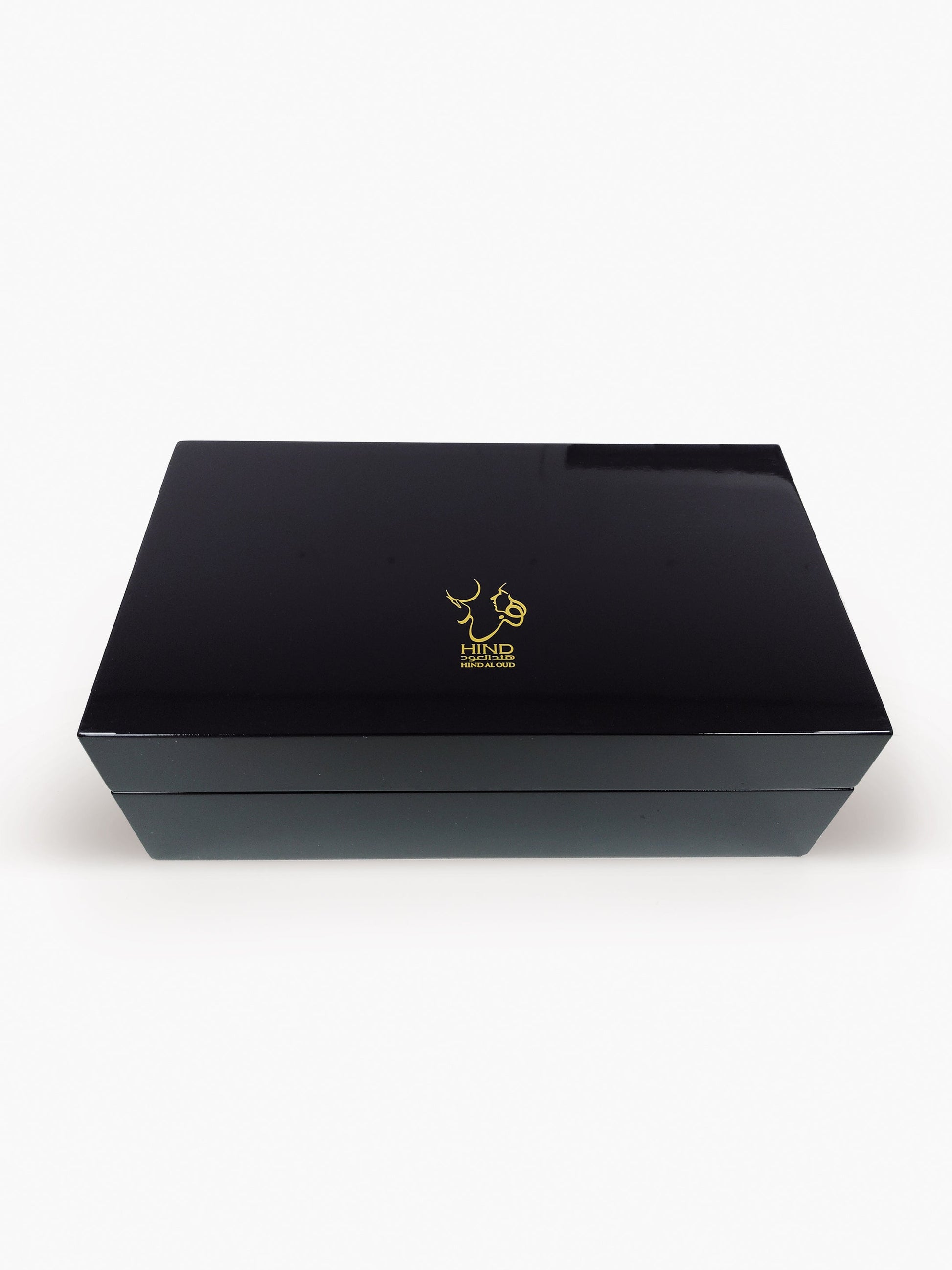 A sleek, rectangular black Emarati Musk Trio Shield Edition Gift Box by Hind Al Oud showcases a gold abstract logo on the lid, set against a white background—ideal for presenting your favorite fragrances.