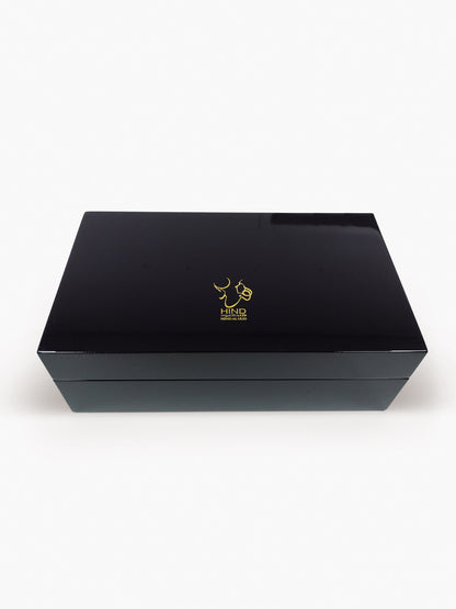 A sleek, rectangular black Emarati Musk Trio Shield Edition Gift Box by Hind Al Oud showcases a gold abstract logo on the lid, set against a white background—ideal for presenting your favorite fragrances.