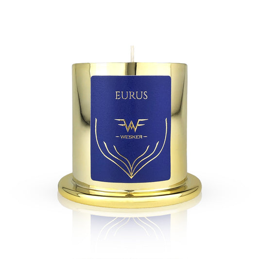 The Eurus Candle - Wesker by Wesker is a shiny gold, hand-poured soy wax candle with a round base. It features a blue label with EURUS and the Wesker logo in gold, and has a visible wick at the top.