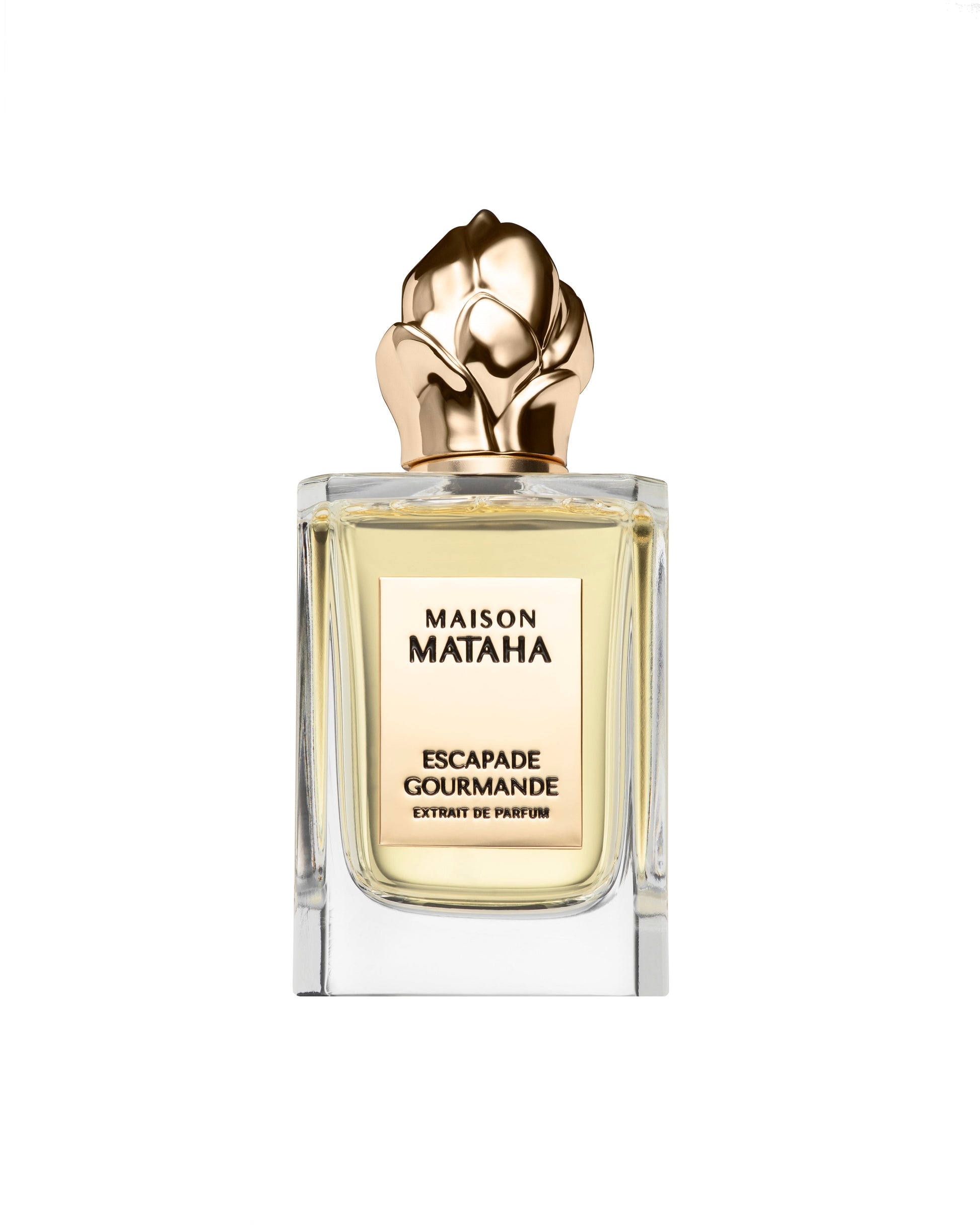 A glass bottle of Maison Mataha Escapade Gourmande Extrait de Parfum, featuring a rose-shaped gold cap and light yellow liquid, set against a white background—a vanilla scent with crème brûlée notes.