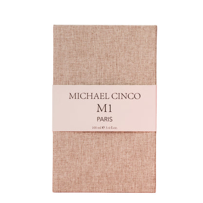 A beige textured rectangular box with a white band labeled Fragrapedia Haus M1 Eau de Parfum 100 ml, exuding a refined floral fragrance of rose and jasmine.