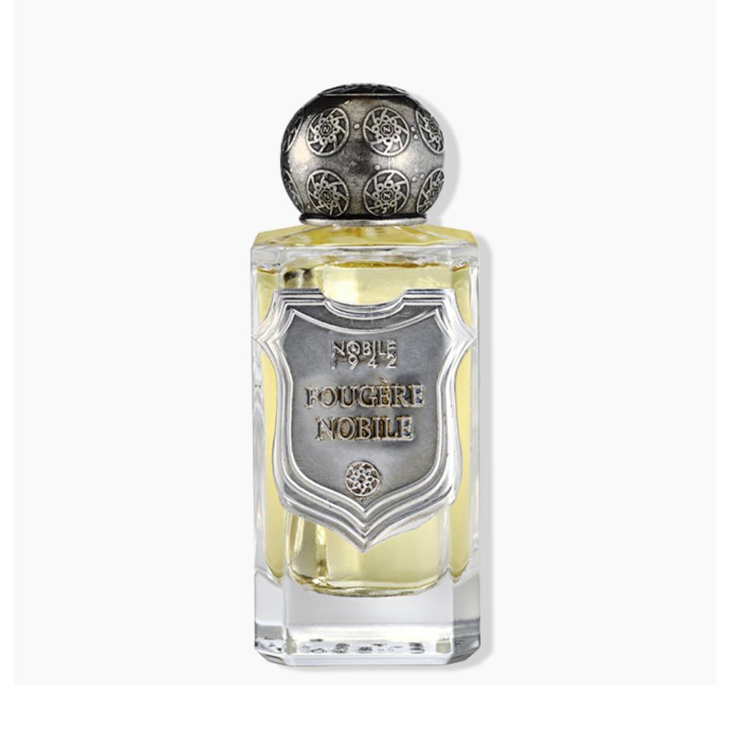 A glass bottle of FOUGERE NOBILE Eau de Parfum by Nobile 1942, with a patterned silver cap and shield, holds light yellow liquid—a refined men’s scent built around an elegant fougère accord.
