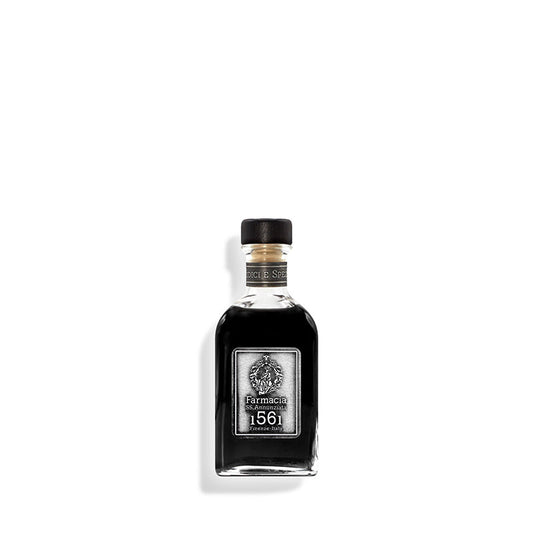 A small glass bottle of Farmacia SS. Annunziata 1561 Medici e Speziali DIFFUSER, with a black cap and vintage-style label, is centered on a white background. Black reeds suggest it diffuses a subtle, peppery scent into the air.