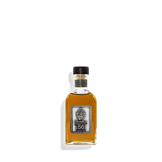 A small clear glass bottle filled with amber liquid, featuring a black cap and a silver label reading "Farmacia 1561" sits against a white background. This is the Mercatanti Diffuser by Farmacia SS. Annunziata 1561.