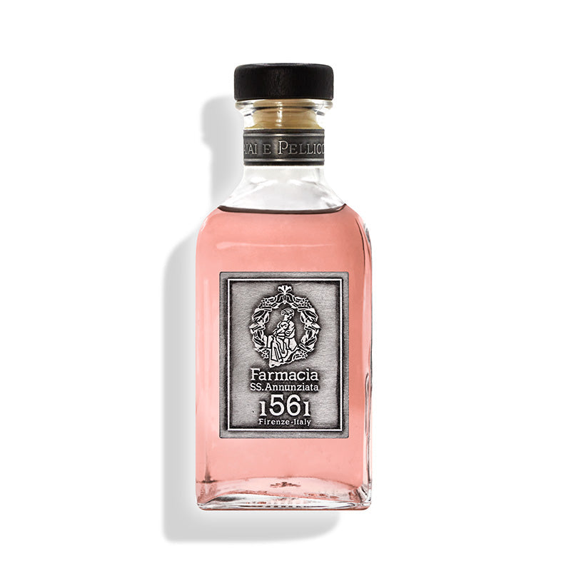 The Vaiai e Pellicciai Diffuser by Farmacia SS. Annunziata 1561 features a clear glass bottle of pink fragrance, a silver label with ornate emblem, black cap, and evokes a rosy scent—set against a white background.