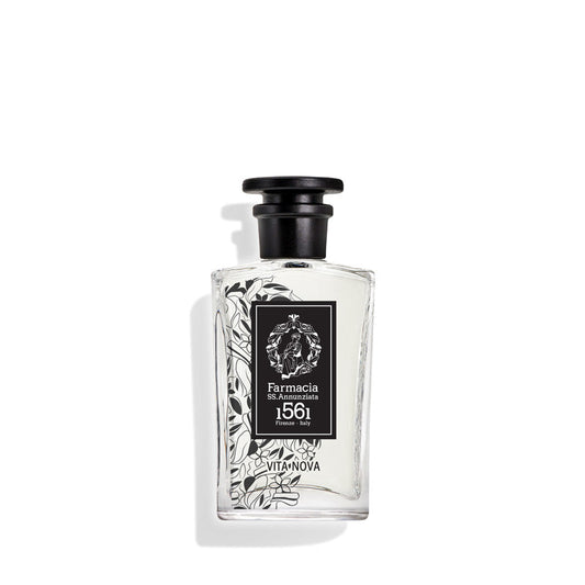 A clear glass Vita Nova Eau de Parfum by Farmacia SS. Annunziata 1561 features a black cap and black-and-white floral design; hints of pink pepper intrigue as the bottle casts a soft shadow on a white background.