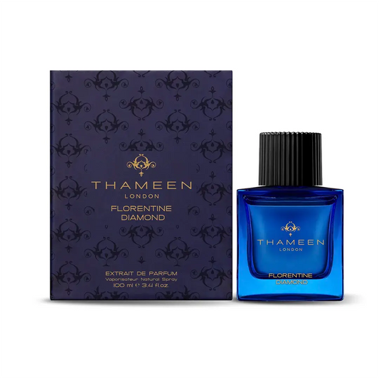 A blue bottle of Florentine Diamond Extrait de Parfum by Fragrapedia Haus stands beside its matching navy and gold patterned box, both displaying the product name in gold. The bottle is topped with a black ribbed cap.