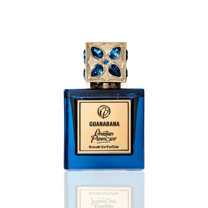 The blue glass Guanabana Extrait de Parfum by Christian Provenzano, featuring a gold gemstone-studded cap, is displayed against white and captures the essence of an Oriental Spicy fragrance.