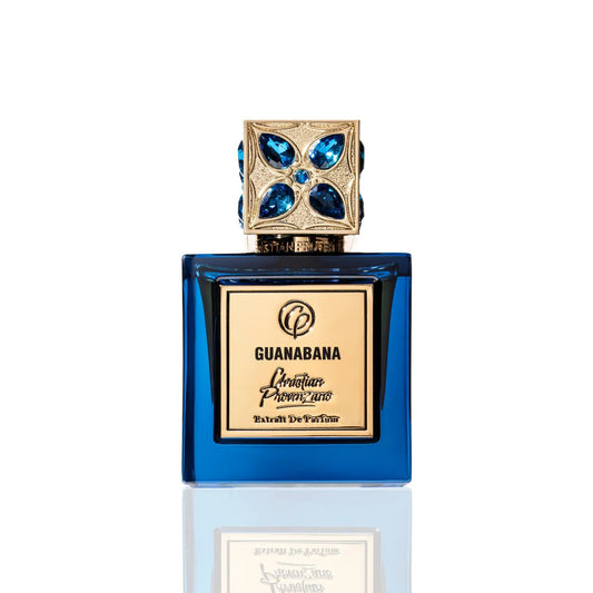 The blue glass Guanabana Extrait de Parfum by Christian Provenzano, featuring a gold gemstone-studded cap, is displayed against white and captures the essence of an Oriental Spicy fragrance.