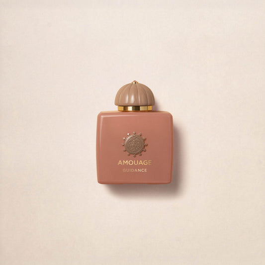 A square, blush-pink luxury bottle of Fragrapedia Haus Guidance Eau de Parfum features a gold cap and detailing, displayed against a light beige background.
