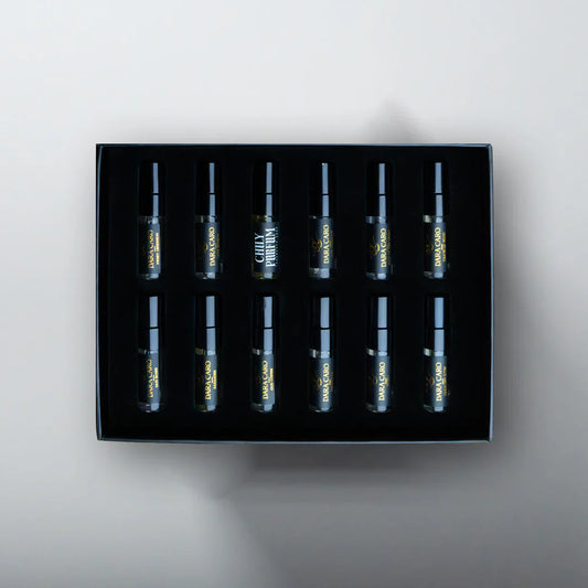 Set of eight small bottles in a black box on a light gray background