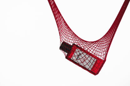 A red bottle of Divina Eau de Parfum - Paradis Des Sens by PARADIS DES SENS, featuring a white label, rests in a red mesh bag against a white background, evoking the indulgent essence of its gourmand fragrance.