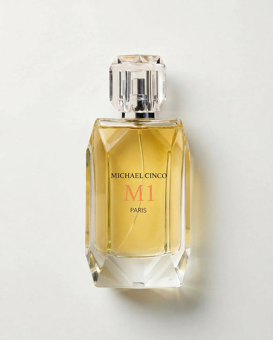 Michael Cinco M1 Paris perfume bottle with a faceted clear glass design, filled with golden-yellow liquid, on a light gray background.