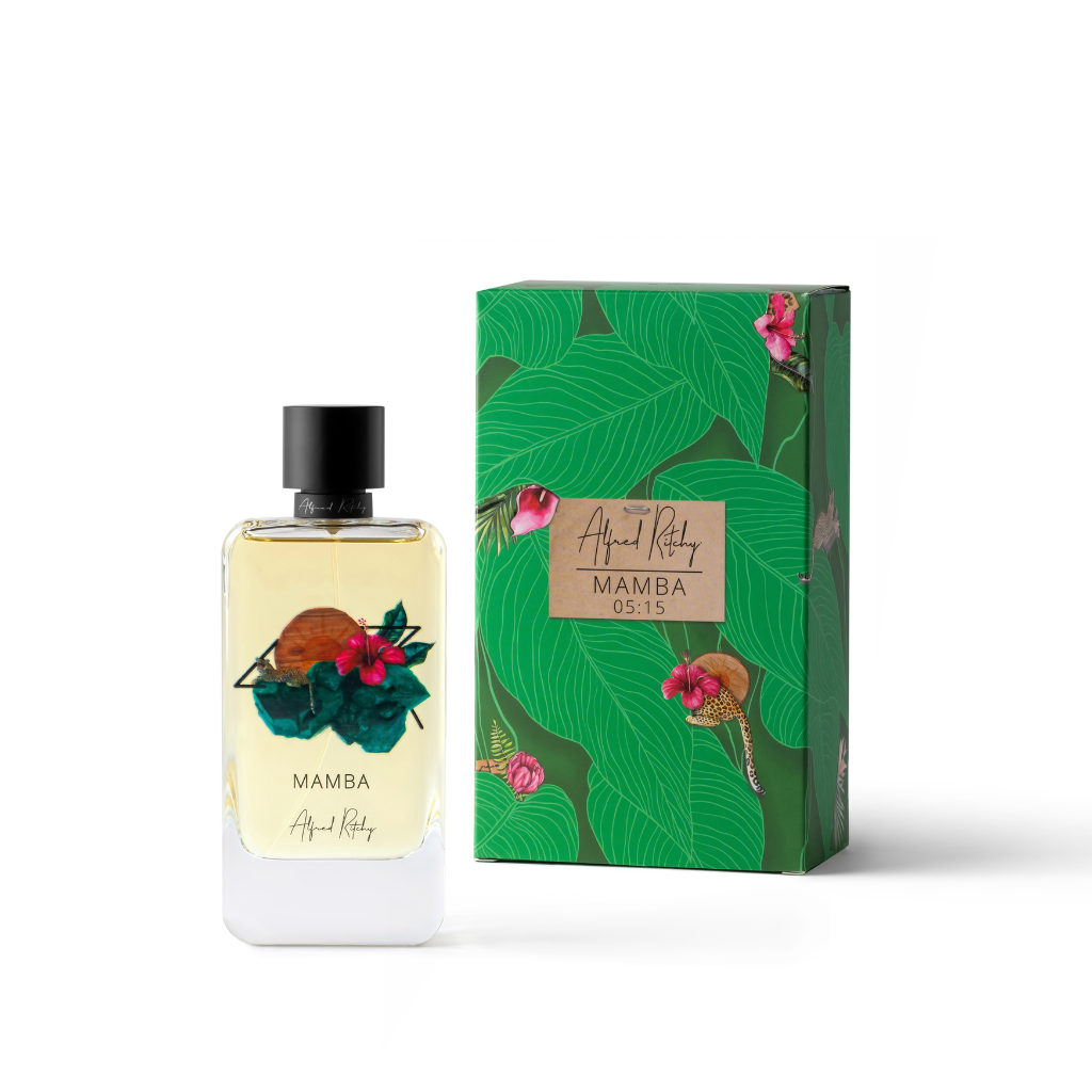 A green MAMBA Eau de Parfum bottle by Alfred Ritchy, with floral and sun designs, is shown beside its matching box decorated with bold leaves, pink flowers, jasmine hints, and labeled “Alfred Ritchy” and “MAMBA 05:15.”.