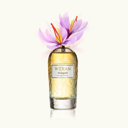 A bottle of Melogold Eau de Parfum by Fragrapedia Haus, adorned with delicate purple flowers and orange stamens atop, set against a light neutral background—an homage to its violet saffron scent.