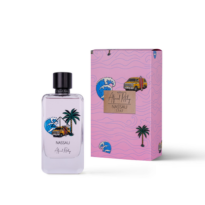 A clear 100ml NASSAU Eau de Parfum bottle by Alfred Ritchy stands beside a matching pink box featuring tropical illustrations—palm trees, waves, a yellow bus, and an island scene—reflecting its pink sand-inspired fragrance.