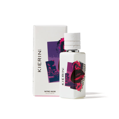 A white bottle of Kierin Nitro Noir Eau de Parfum is displayed in front of its box, both featuring bold abstract purple and red designs with cityscape and lips—an eye-catching choice for any luxury fragrance collection.