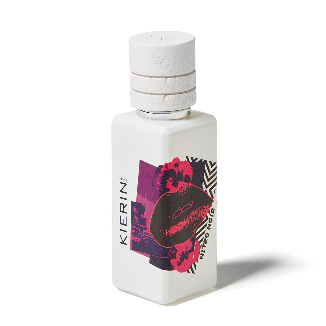 A white rectangular bottle with a textured cap, Nitro Noir Eau de Parfum by Kierin features a bold graphic label with lips, abstract shapes, and black, pink, and red accents—an icon among luxury scents.