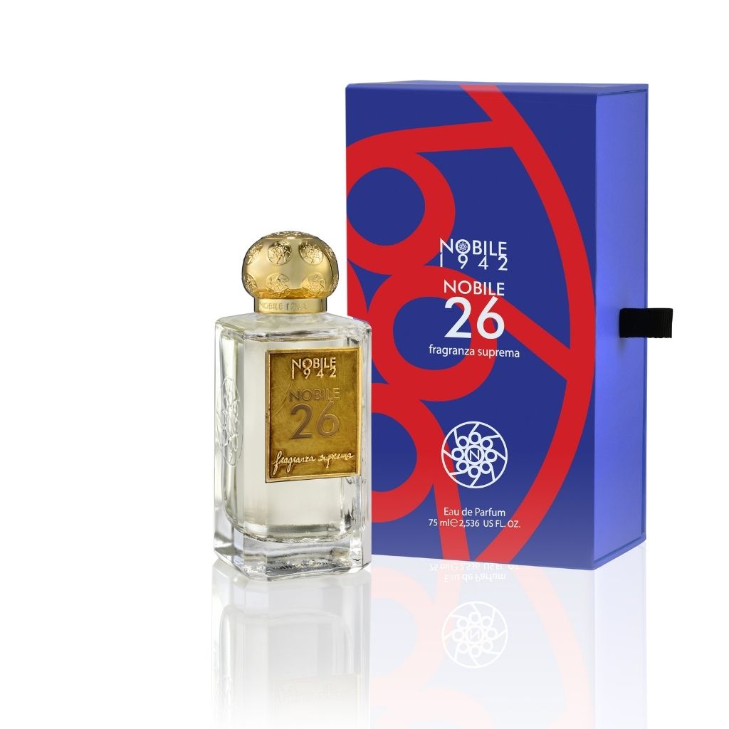 NOBILE 26 Eau de Parfum by Nobile 1942 comes in a glass bottle with a gold cap and label, alongside a blue box with red design and white “Nobile 1942 Nobile 26 fragranza suprema” text. This oriental woody scent features burnt woods and coffee notes, 75 ml.