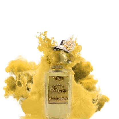 The CAFE CHANTANT Eau de Parfum by Nobile 1942, in a clear glass bottle with a gold label and cap topped by a cream flower, is set amid swirling yellow smoke on white, evoking the luxurious allure of this gourmand fragrance.