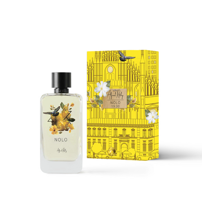 A clear Alfred Ritchy NOLO Eau de Parfum (100ml) with a floral label stands next to a bright yellow box adorned with flowers, a cathedral, and city scenes, labeled “NOLO Eau de Parfum - Alfred Ritchy.”.