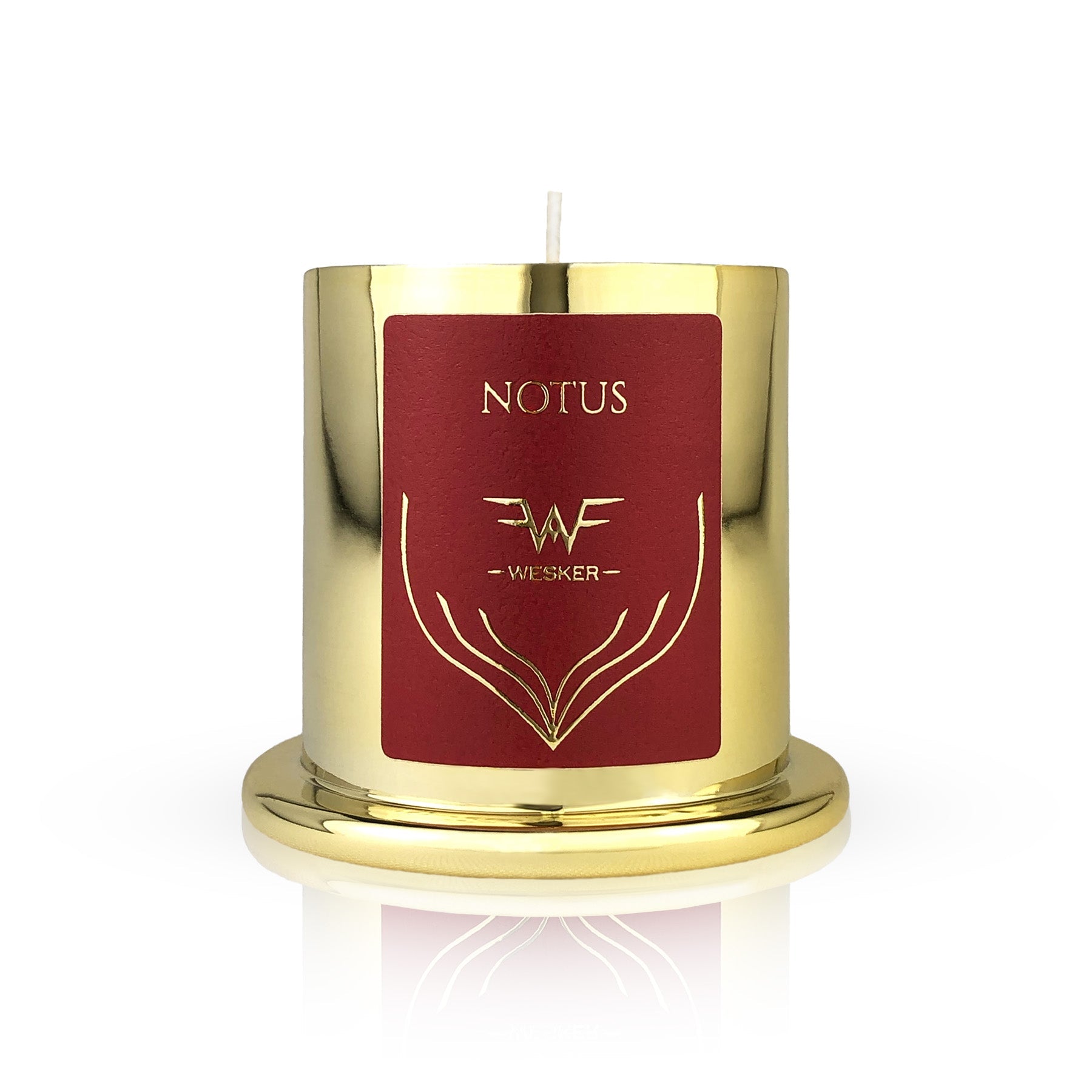 The Notus Candle - Wesker by Wesker is a gold metallic candle with a red label featuring gold designs and "WESKER" below "NOTUS." Infused with a desert scent, it sits on a matching gold base against a white background.