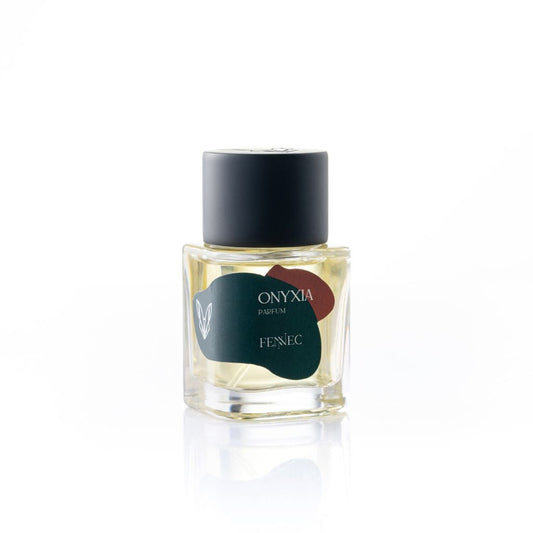 A small glass perfume bottle with a black cap and a green-burgundy label displays "Onyxia Parfum" by Fennec, plus a white fennec fox head logo—honoring this North African animal’s large ears.