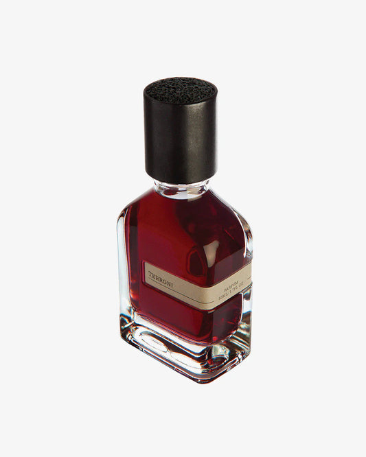 A glass bottle of Terroni Eau de Parfum by Fragrapedia Haus, filled with deep red liquid and topped with a black cap, evokes rich soil and roots; it's displayed against a white background.