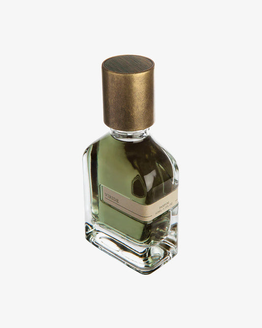 Viridi Eau de Parfum by Fragrapedia Haus comes in a clear glass bottle with green liquid, accented by a gold label and large round metallic gold cap, evoking herbal plants in floral crowns, set against a white background.