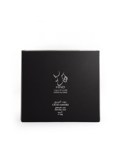 A black square box with white Arabic and English text—Hind Al Oud and Oud Amiri Natural Oud—plus a minimalist animal-heads logo, presents the luxurious scent of premium agarwood from Hind Al Oud.