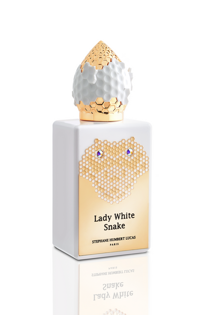 A white floral fragrance inspired by the Lady White Snake legend. Presented in a white bottle with gold honeycomb accents, blue gems, and a gold and white cap. Label: Lady White Snake Eau de Parfum - Stephane Humbert Lucas, Fragrapedia Haus.