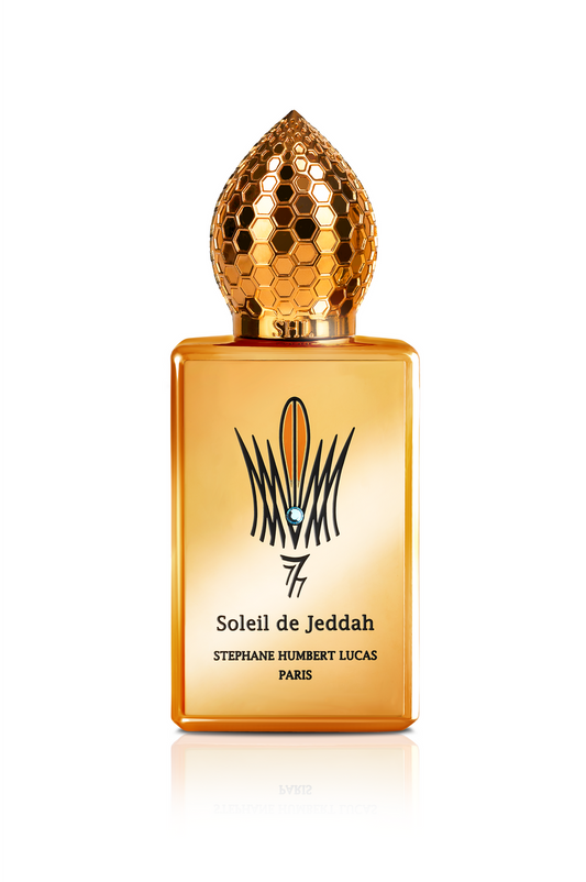 A golden rectangular bottle with a dome-shaped honeycomb cap, labeled “Soleil de Jeddah Mango Kiss Eau de Parfum - Stephane Humbert Lucas” by Fragrapedia Haus, features a black and gold decorative logo for an elegant, gourmand impression.