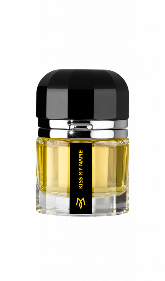 A clear glass bottle with yellow liquid, a black and silver cap, and a black label reading "KISS MY NAME" in gold—a refined Kiss My Name Eau de Parfum by Ramon Monegal.