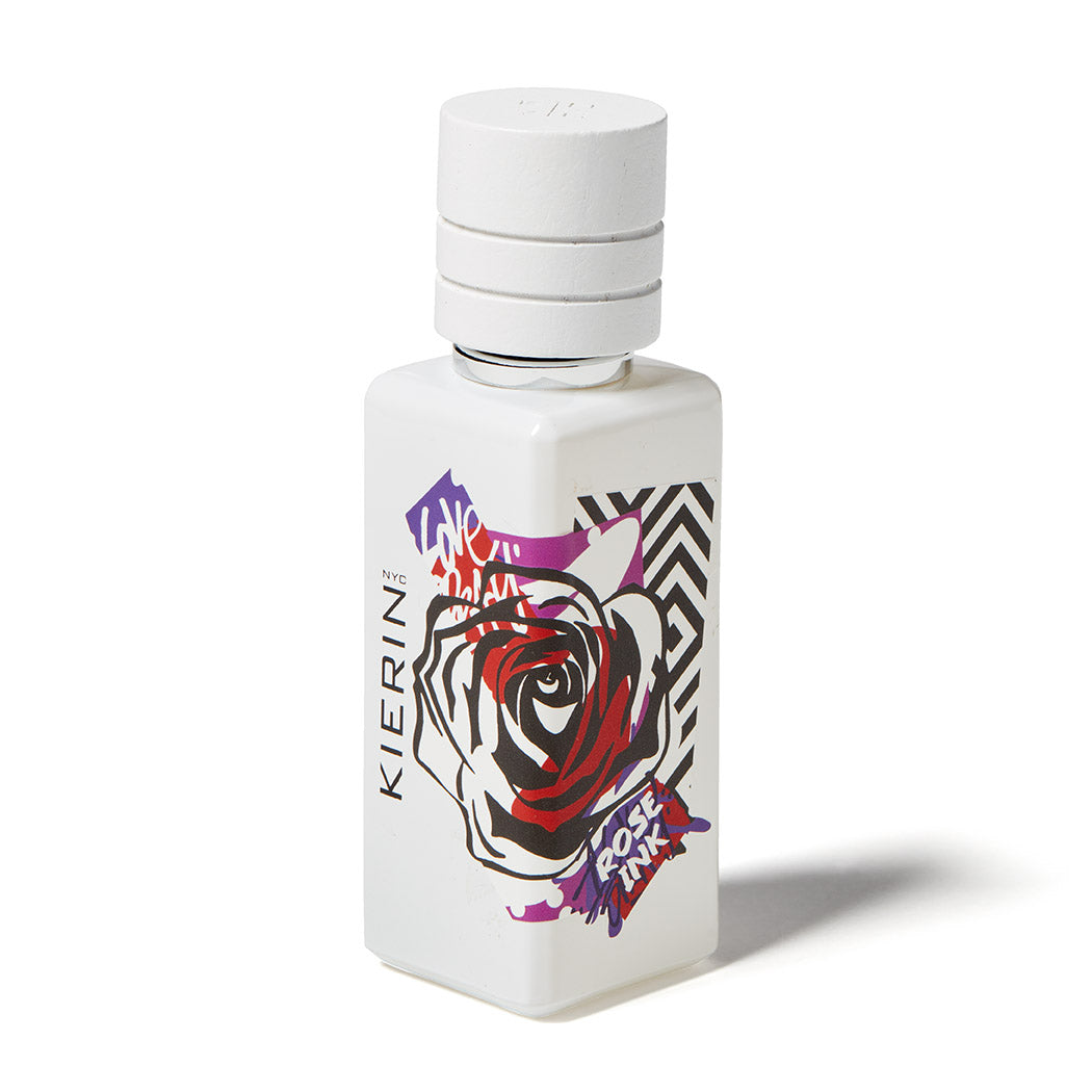 The Kierin Rose Ink Eau de Parfum features a white bottle with bold, colorful graffiti-style artwork—a large rose and “Love Always”—paired with a vibrant, woodsy floral unisex scent.