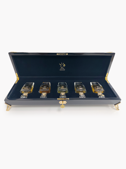 A luxurious black case with gold accents displays the Hind Al Oud Royal Precious Collection—five elegant perfumes arranged on dark blue velvet, making it the perfect gift set from Hind Al Oud.