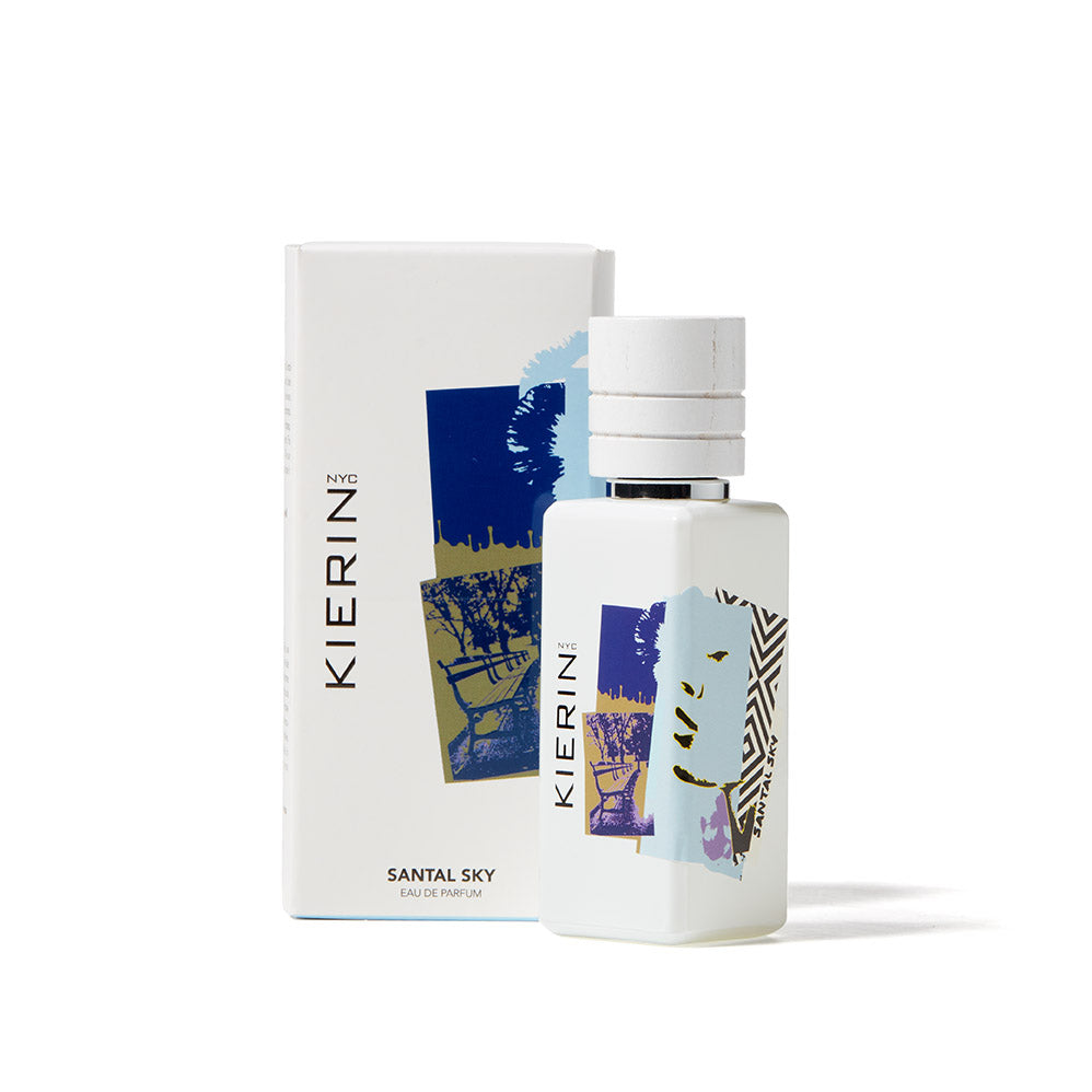 A bottle of Santal Sky Eau de Parfum by Kierin stands before its matching box, both showcasing abstract blue, gold, and black designs on white, echoing the sandalwood notes found in this woody fragrance.