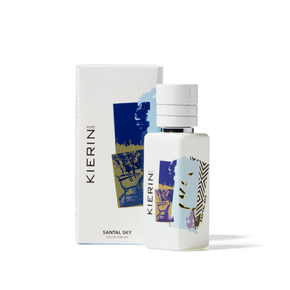 A bottle of Santal Sky Eau de Parfum by Kierin stands before its matching box, both showcasing abstract blue, gold, and black designs on white, echoing the sandalwood notes found in this woody fragrance.
