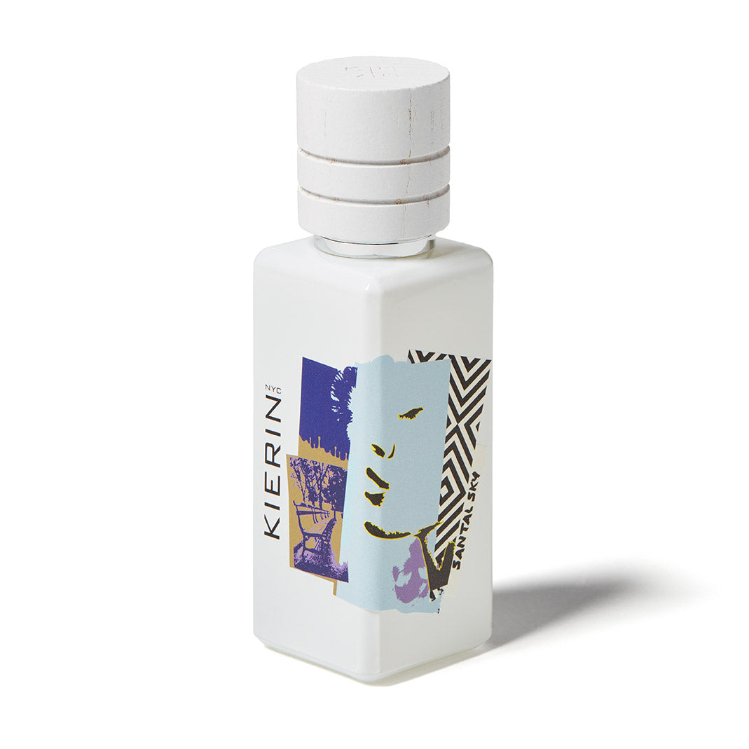 A white Santal Sky Eau de Parfum bottle by Kierin stands upright on a white background, featuring a cylindrical cap, abstract blue, beige, and black artwork, and delivers a woody sandalwood fragrance.