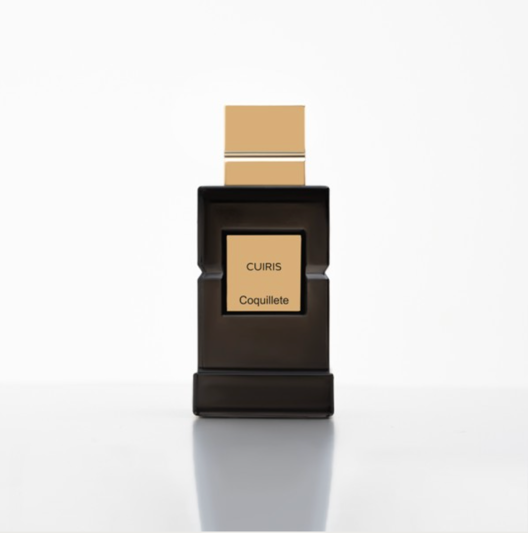 A rectangular black bottle with a square beige label reading "CUIRIS Eau de Parfum - Coquillete" and a matching beige cap exemplifies modern French perfumery by Coquillete, set against a plain white background.