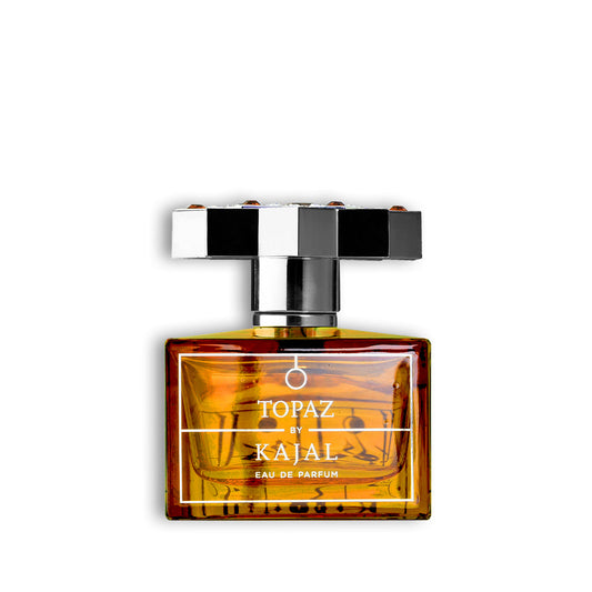 A rectangular glass bottle of Topaz Eau de Parfum by Kajal Perfumes Paris with amber-yellow liquid and a black-and-white checkered cap sits on a white background—an elegant symbol of love in fragrance form.