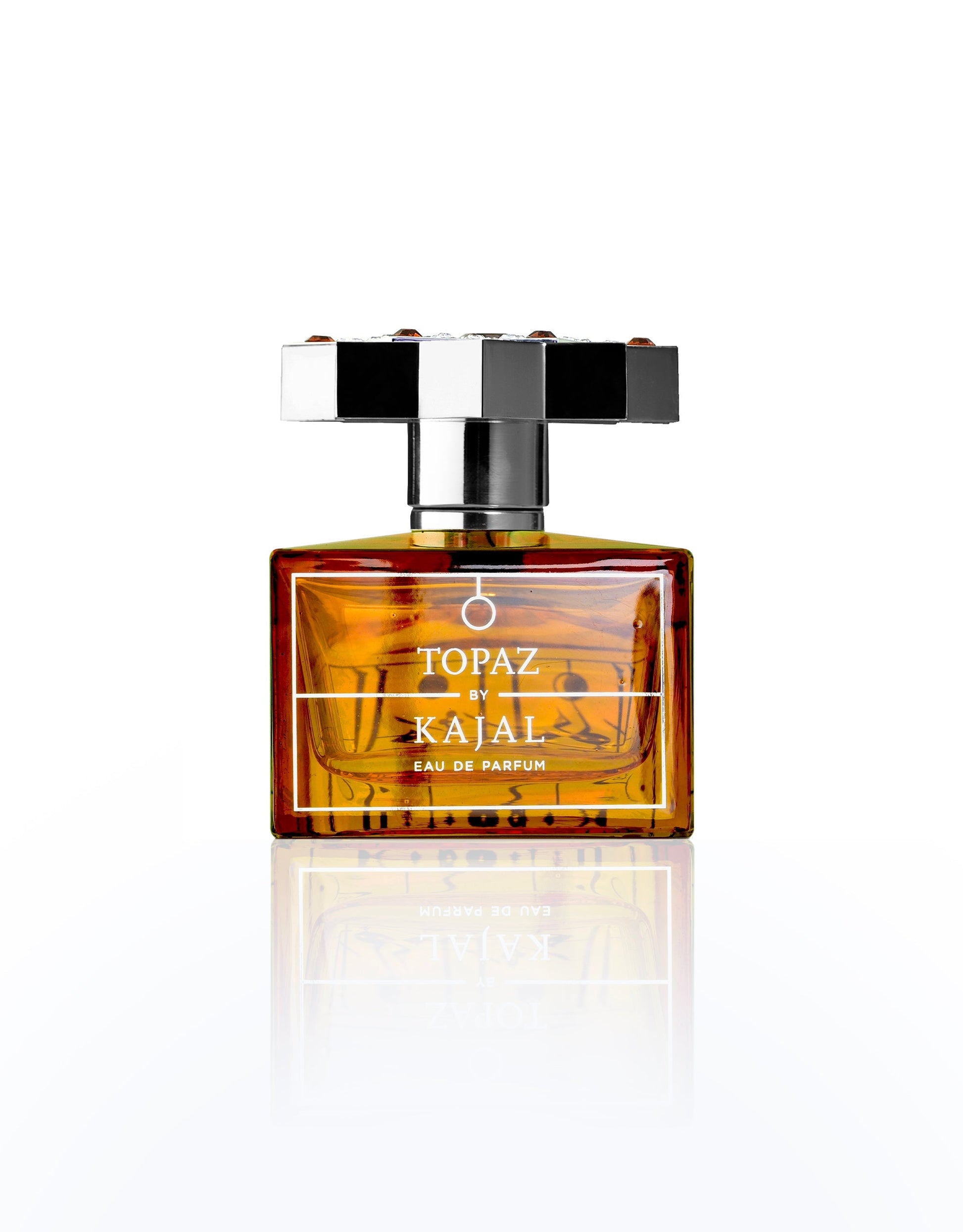 A rectangular amber glass bottle of Topaz Eau de Parfum by Kajal Perfumes Paris, featuring a bold silver and black geometric cap, is displayed against a white background—a symbol of love and passion, like an eternal flame.