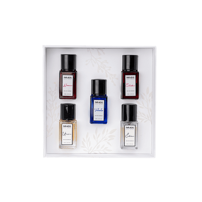 A gift box featuring the PARADIS DES SENS Travel Set—five uniquely colored, labeled perfume bottles arranged in rows on a white background with delicate leaf patterns for an elegant fragrance experience.
