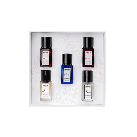 A gift box featuring the PARADIS DES SENS Travel Set—five uniquely colored, labeled perfume bottles arranged in rows on a white background with delicate leaf patterns for an elegant fragrance experience.