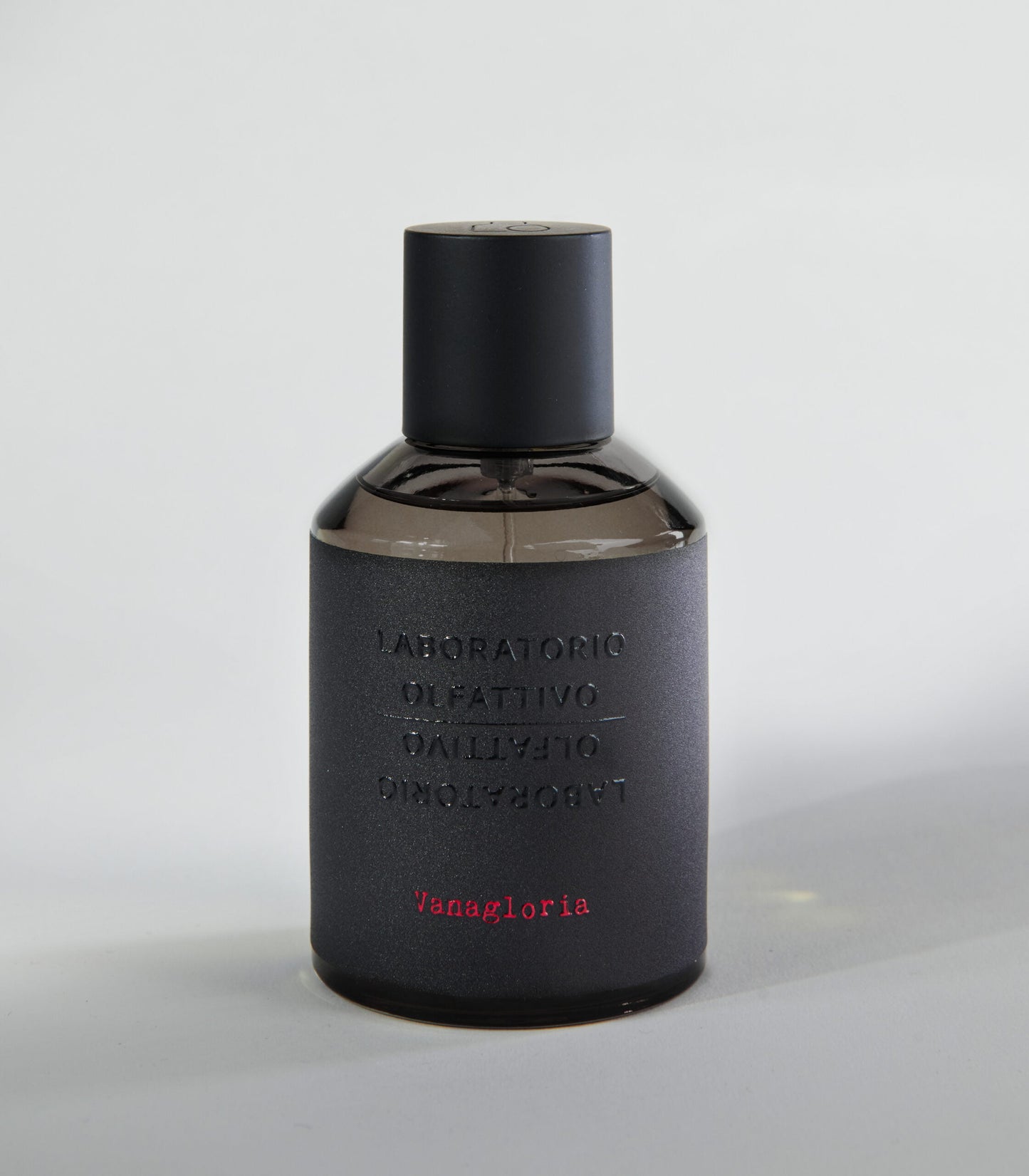 A dark, matte bottle of Vanagloria by Laboratorio Olfattivo, with embossed text and minimalist design, hints at a sophisticated vanilla scent made from fine Bourbon vanilla, set against a plain light gray background.