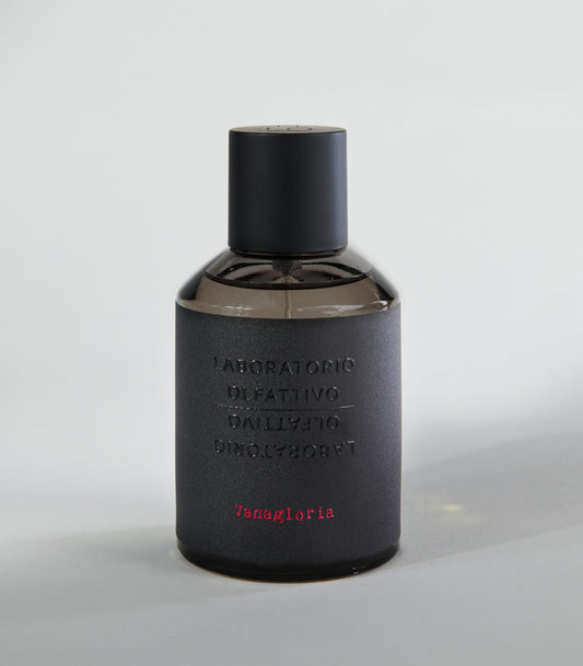 A dark, matte bottle of Vanagloria by Laboratorio Olfattivo, with embossed text and minimalist design, hints at a sophisticated vanilla scent made from fine Bourbon vanilla, set against a plain light gray background.